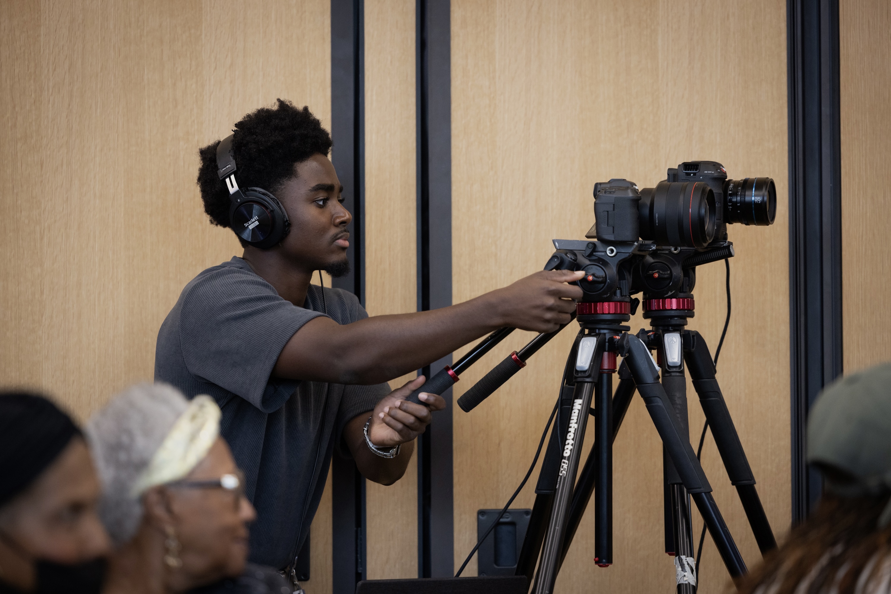 Videographer adjusting a camera on a tripod during a shoot