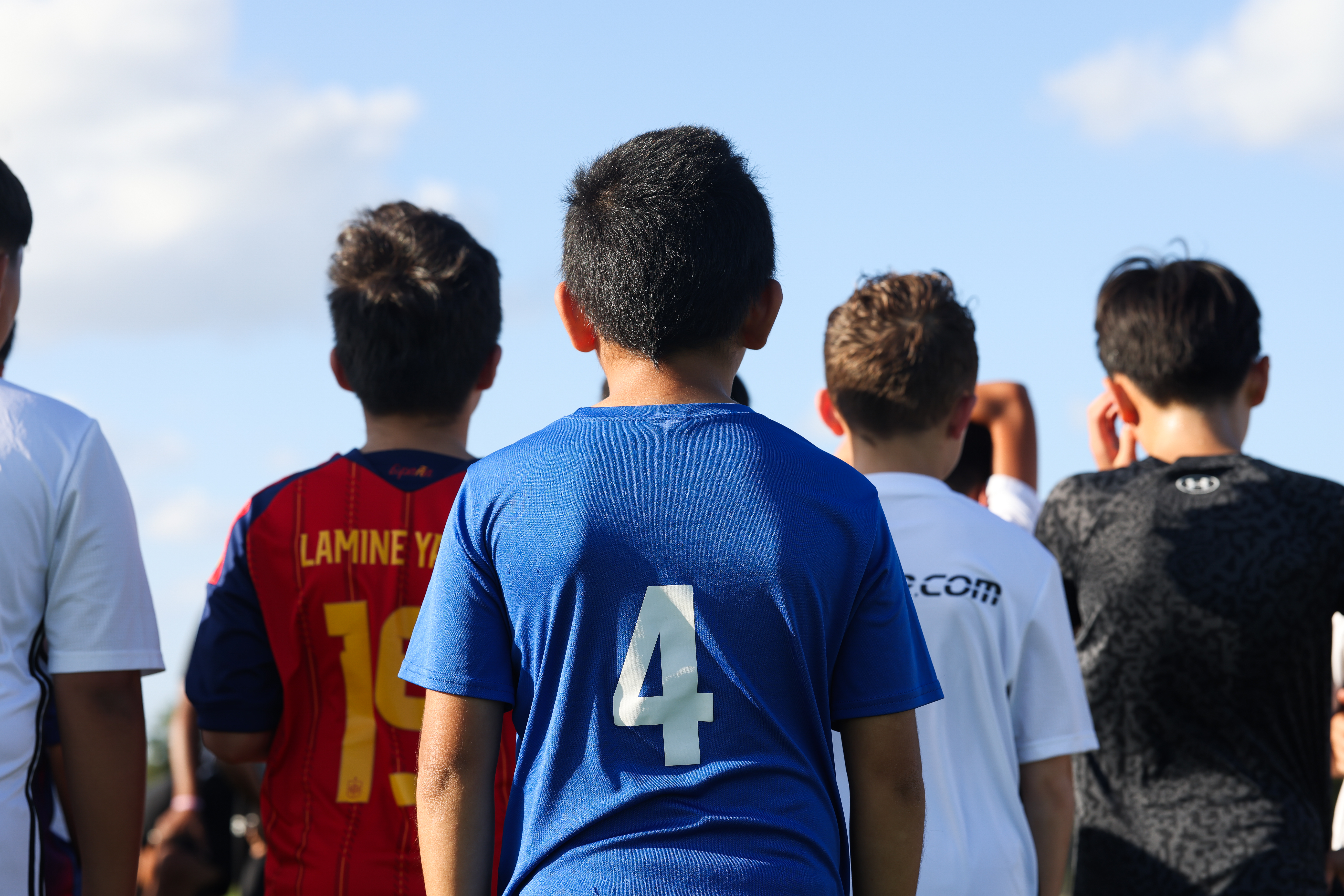 Young soccer player viewed from behind, standing with teammates on the field