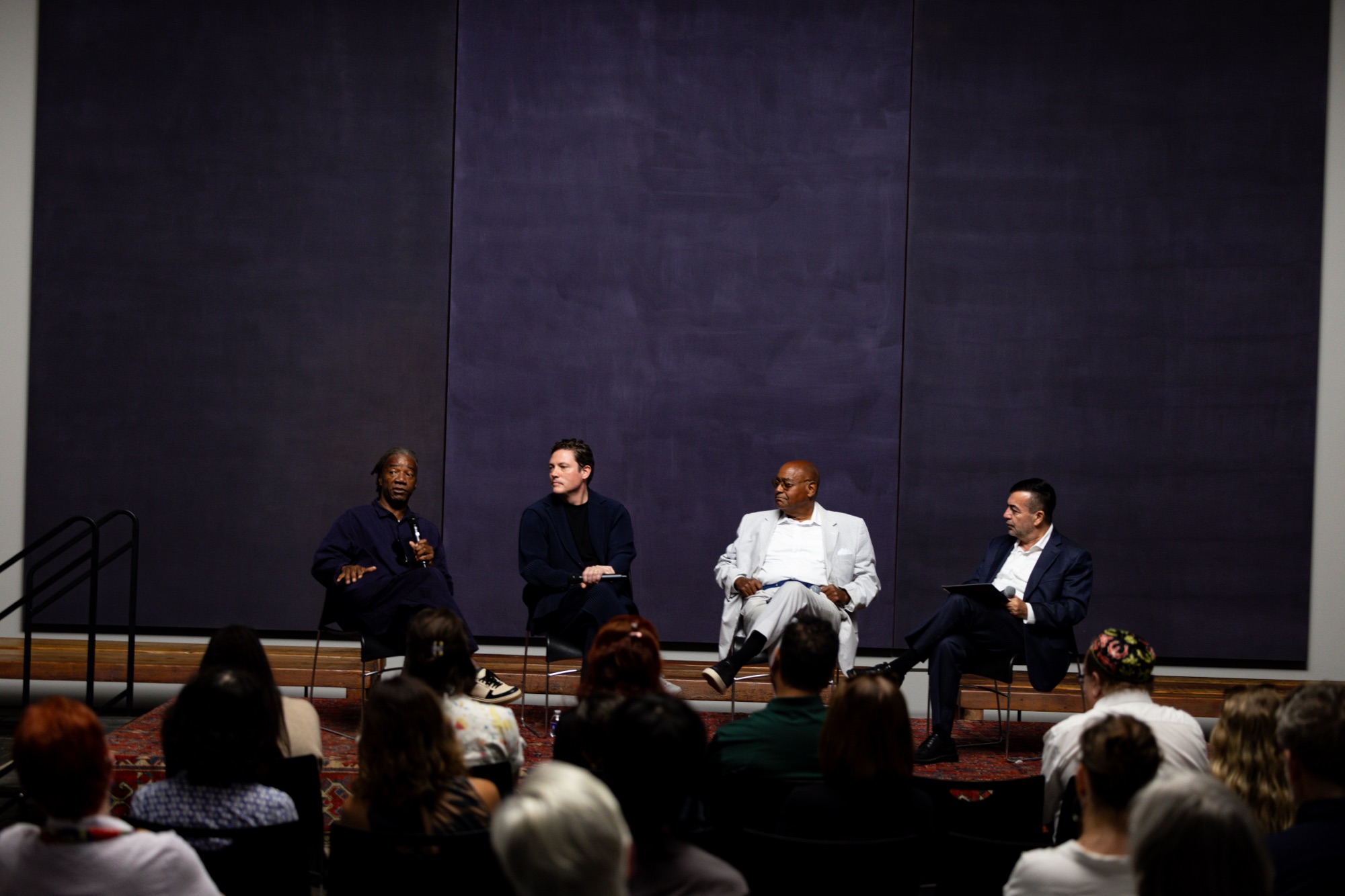 Panel discussion on stage at the Rothko Chapel with a large Rothko painting behind the speakers
